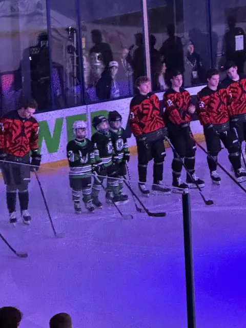 Mites players stand on the ice with Liberty University players during pregame introductions